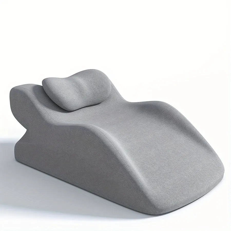 A stomach sleeper pillow shown in light grey, designed for reading or phone use in a prone position.