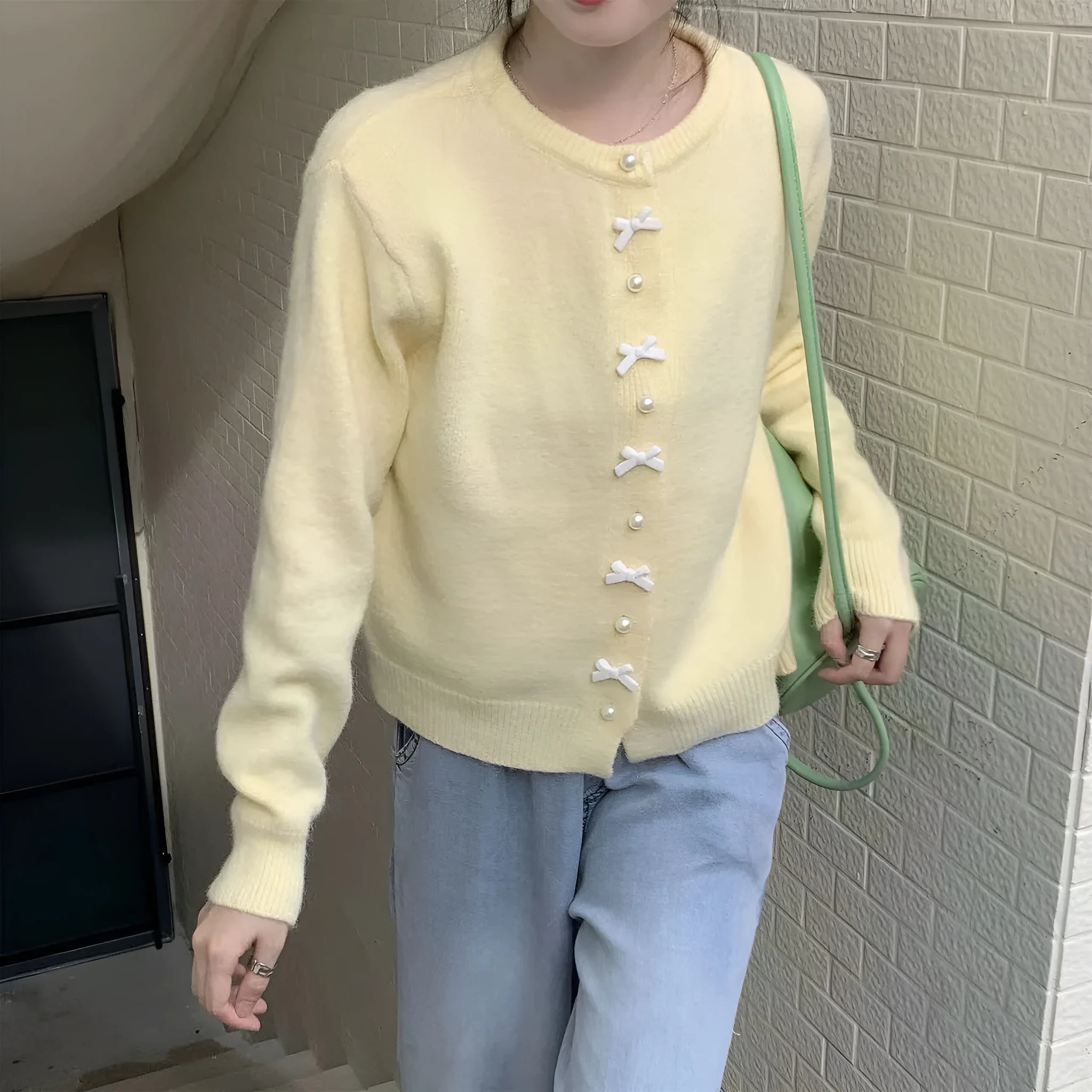 Women's cashmere cardigan sweater with bow and pearl buttons across chest in light blue colour