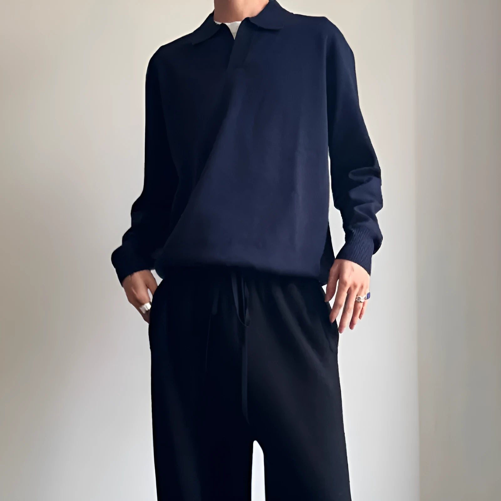 Man wearing a milky white pure wool polo sweater with a lapel collar and loose long sleeves.