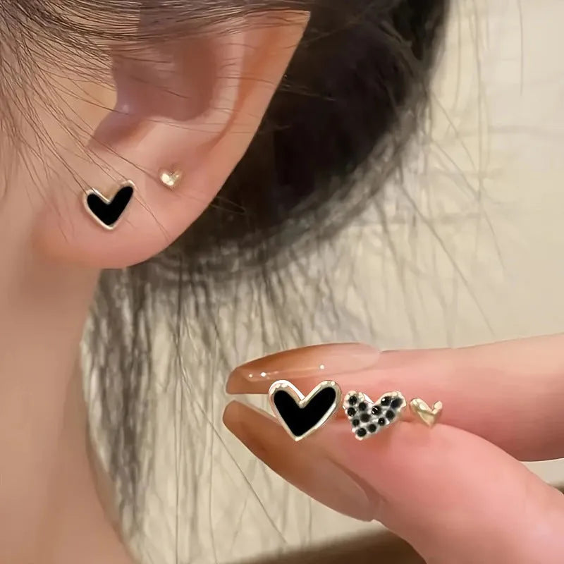 Three pairs of heart-shaped earrings with electroplated alloy construction in gold, black, pink and black-white colours
