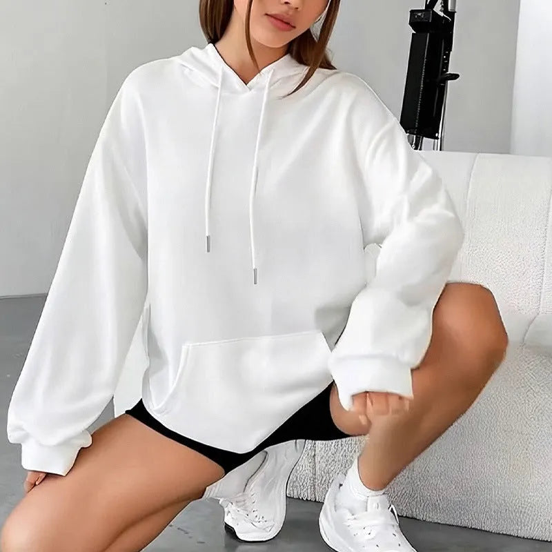 Woman wearing a loose grey drawstring waist sweatshirt with front pockets and long sleeves.