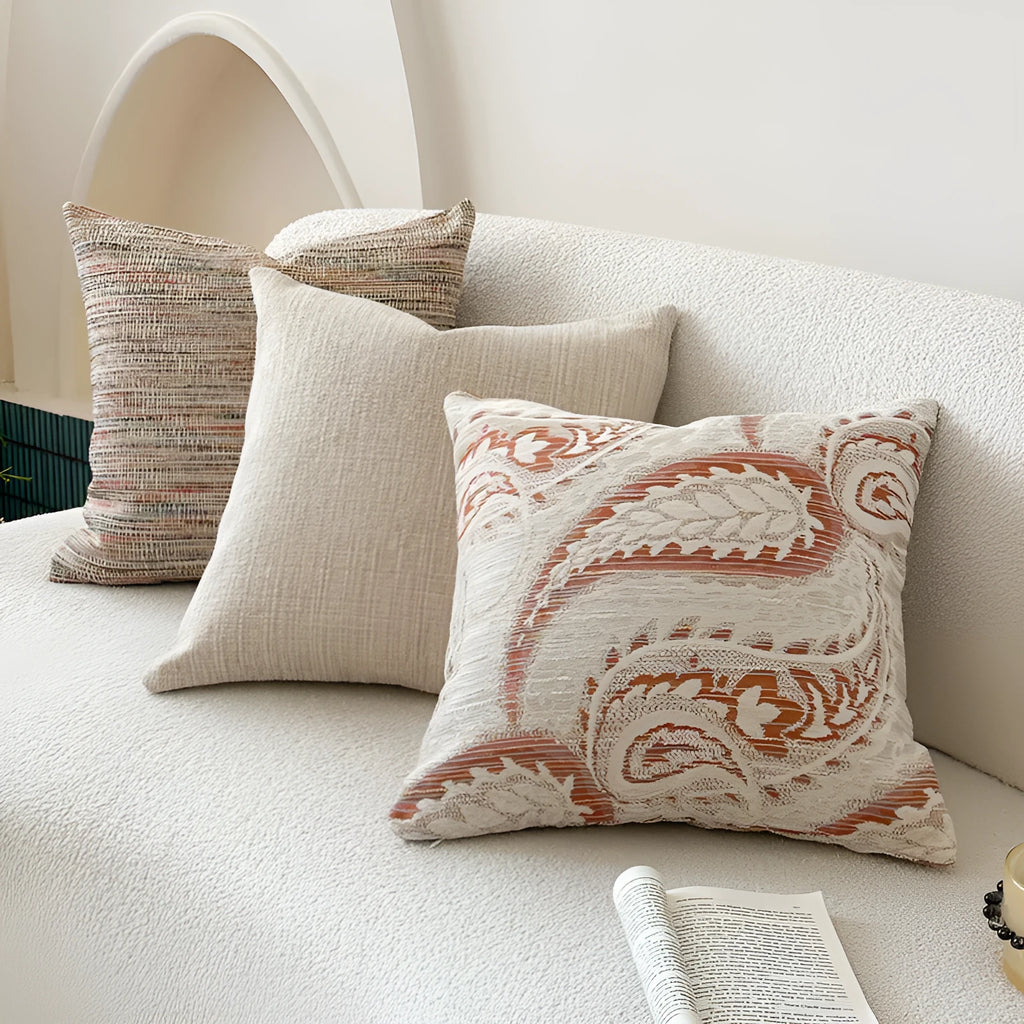 American-style jacquard cushion cover with paisley and flower pattern in amber colours on a sofa.