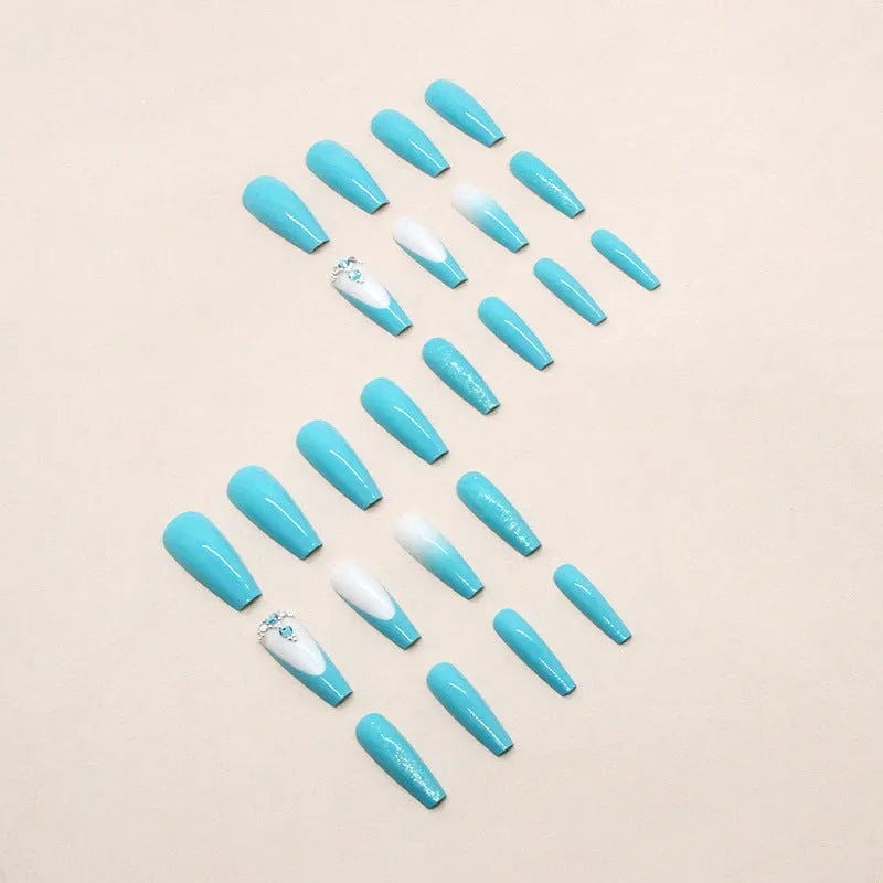 Long solid colour ballet artificial nails with blue diamond glitter glue on a pink background