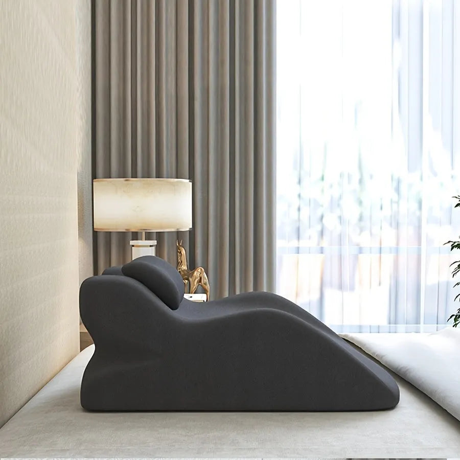 A stomach sleeper pillow shown in light grey, designed for reading or phone use in a prone position.