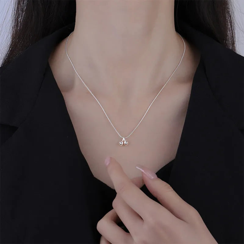 Silver necklace with cherry pendant on an adjustable snake bone chain.