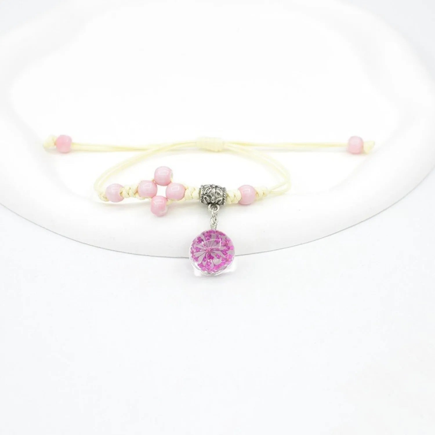 Glass bracelet with large colourful beads containing real dried flowers, on a white background.