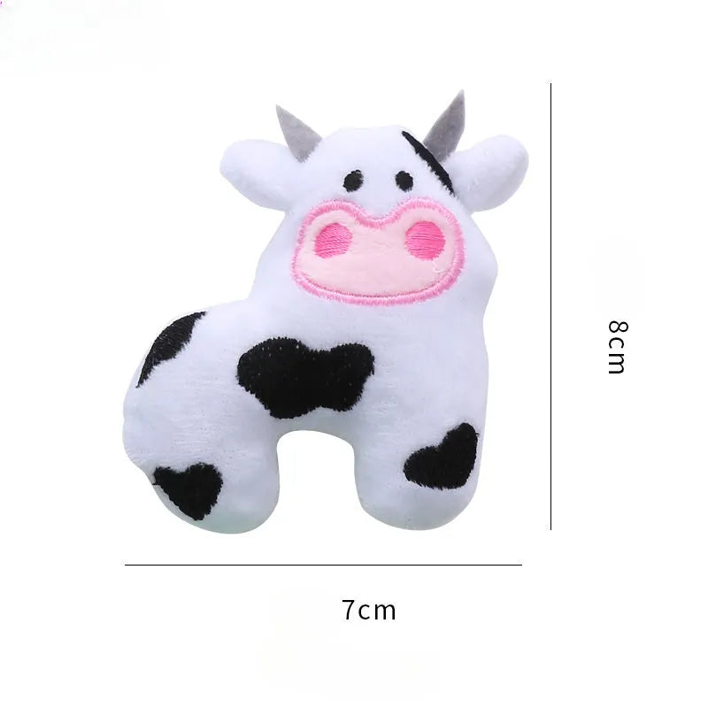 Colourful plush cat toy shaped like a cow, a crocodile, or a parrot on a plain background.