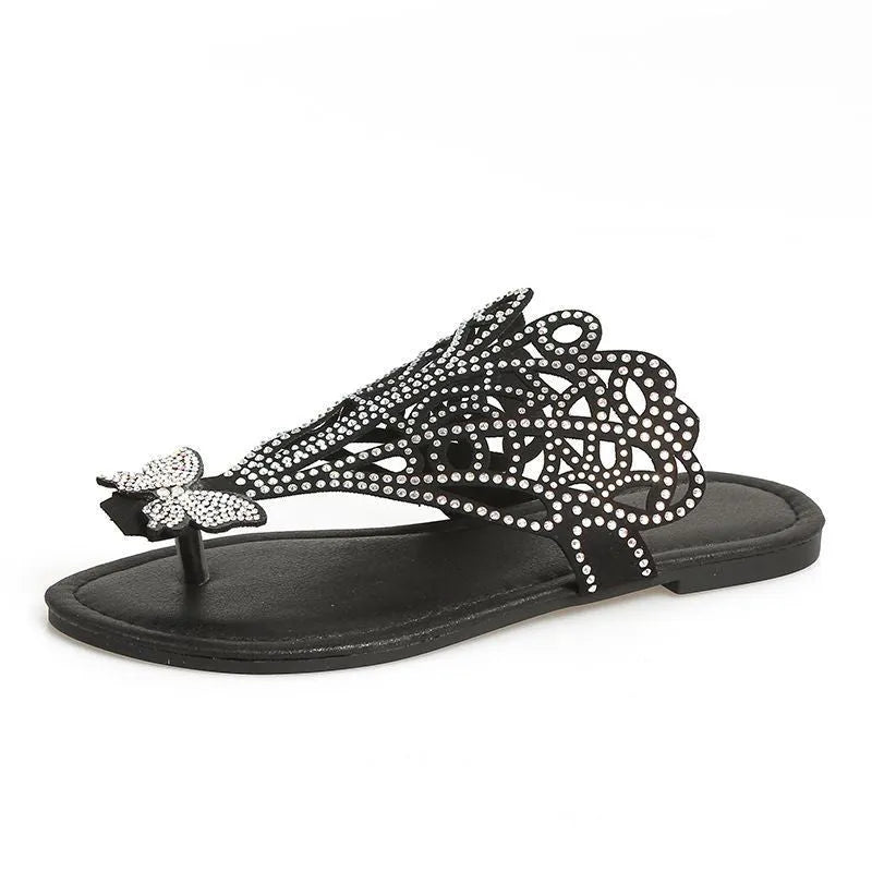 Women's black slip-on sandals with rhinestone decorations and a flat rubber sole.