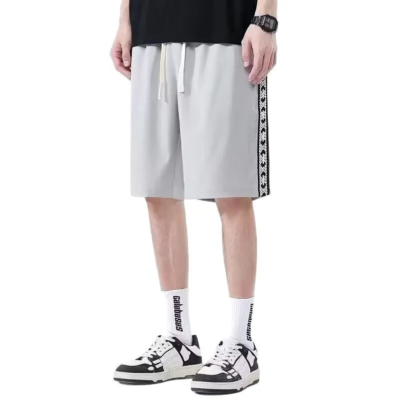 Man wearing loose fit black track pants with an elastic waistband, casual sports style.