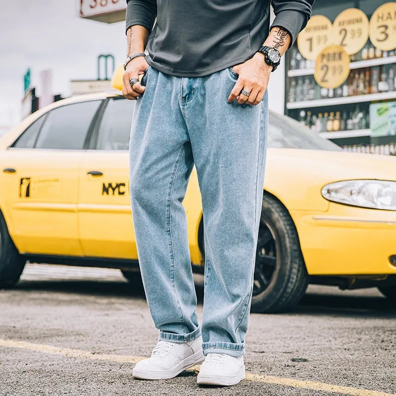 Man wearing dark blue loose straight-cut cotton jeans with a mid-waist and zipper fly.