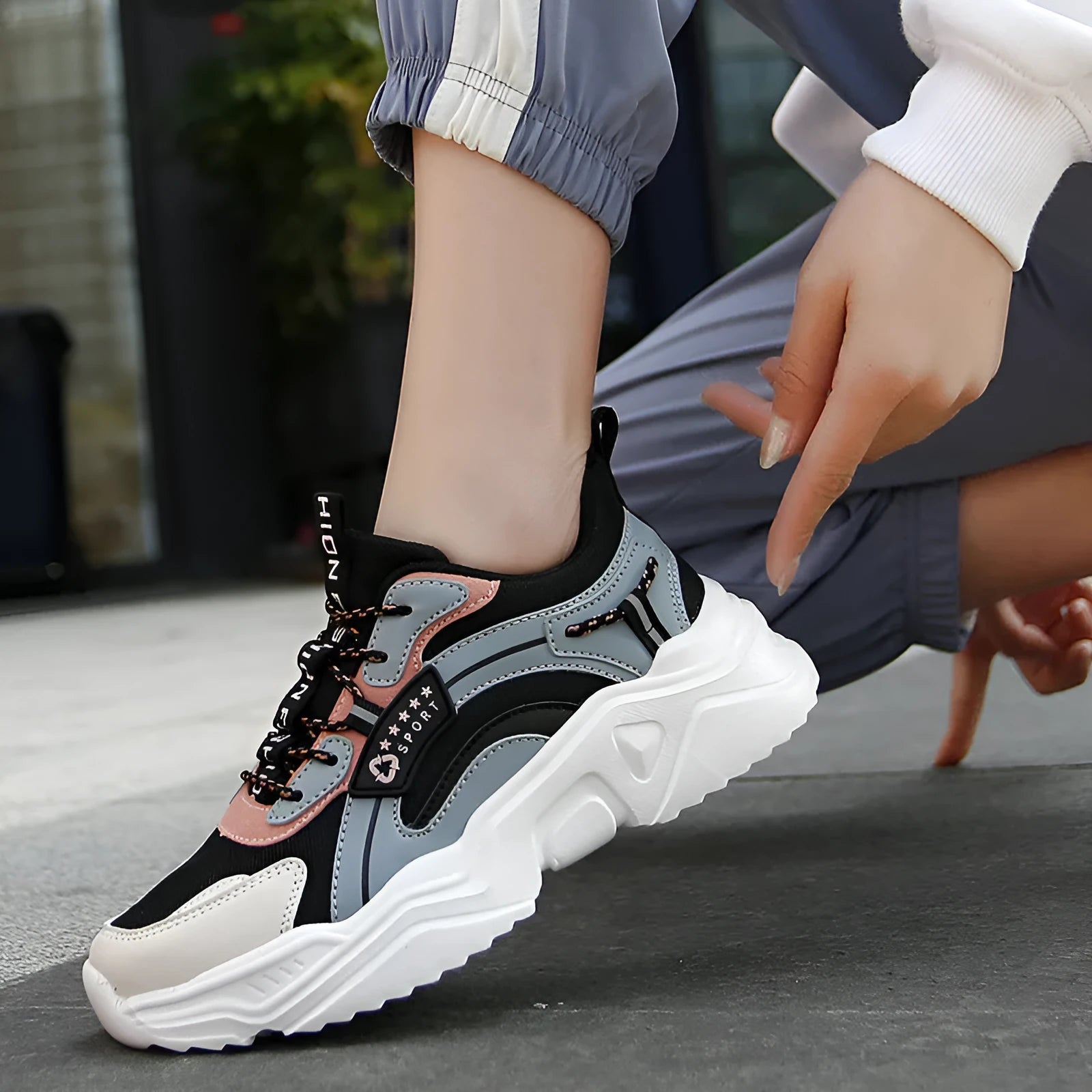 Women's white thick-soled casual sneakers with mesh upper and buckle detail on a light background.