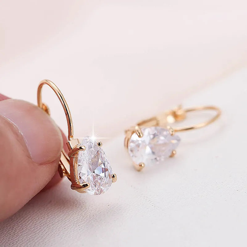 Drop-shaped metal earrings in gold or platinum finish with inlaid gem detailing