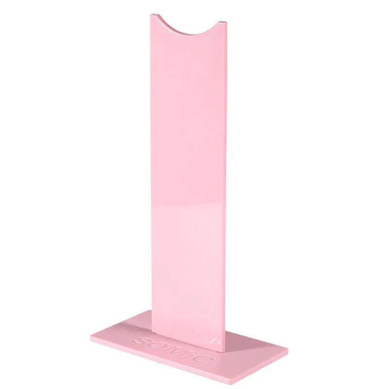 Pink detachable headphone stand for gaming headsets on a desk, shown next to its disassembled parts.
