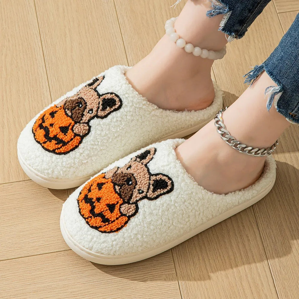 Black and white Halloween pumpkin plush slippers with non-slip rubber soles on a wooden floor