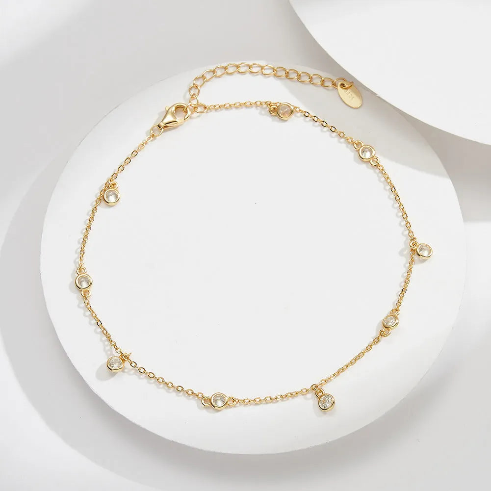 Simple silver anklet with a geometric zirconium pendant in gold colour