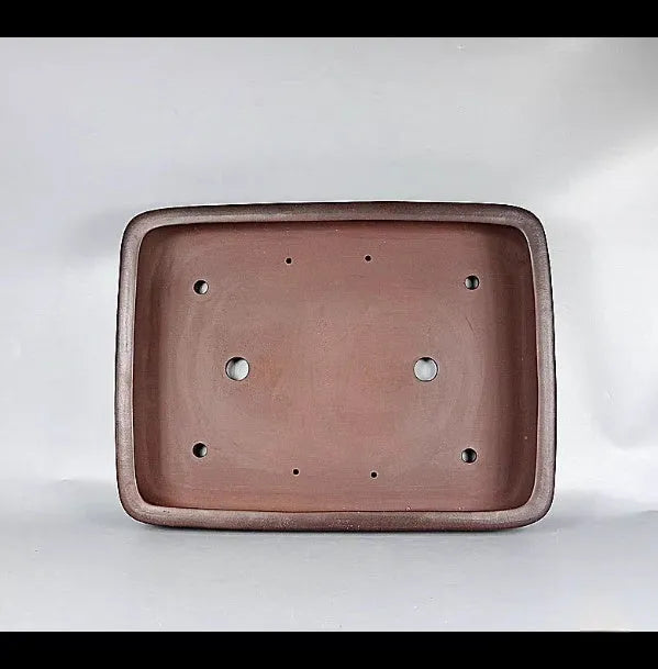 Handmade antique-style rectangular purple clay flower pot on a wooden surface.