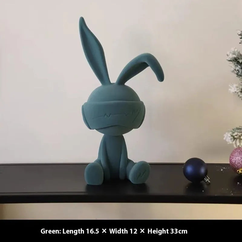 Green resin blindfold rabbit table ornament on a wooden surface.