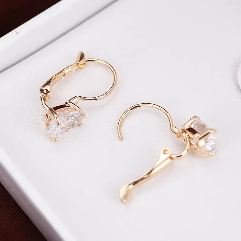 Drop-shaped metal earrings in gold or platinum finish with inlaid gem detailing