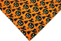 Black and orange reversible triangle dog bandana with Halloween pumpkin and spider web patterns.