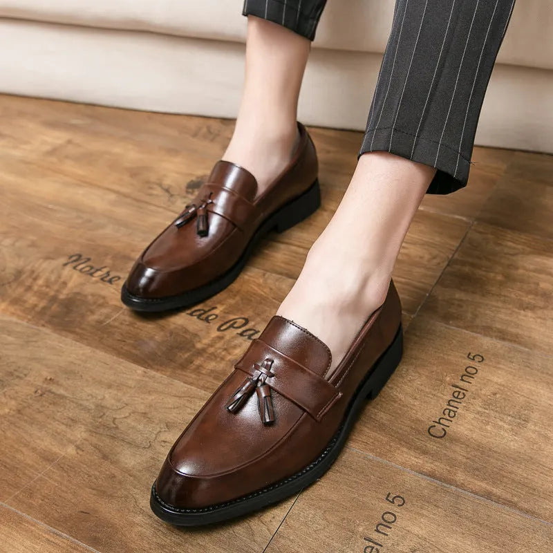 Men's black slip-on business casual shoe with a tassel detail on a low-top artificial PU upper.