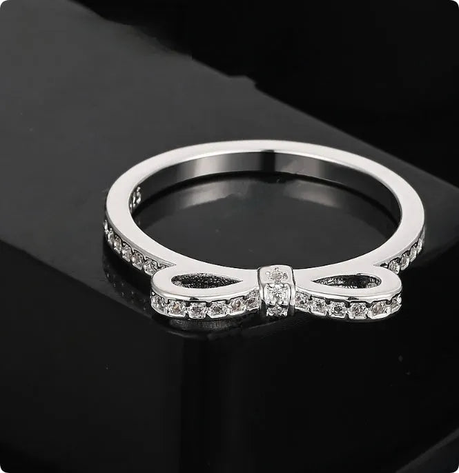 Silver bow-shaped ring with rhinestone zircon crystal detailing showing side profile view