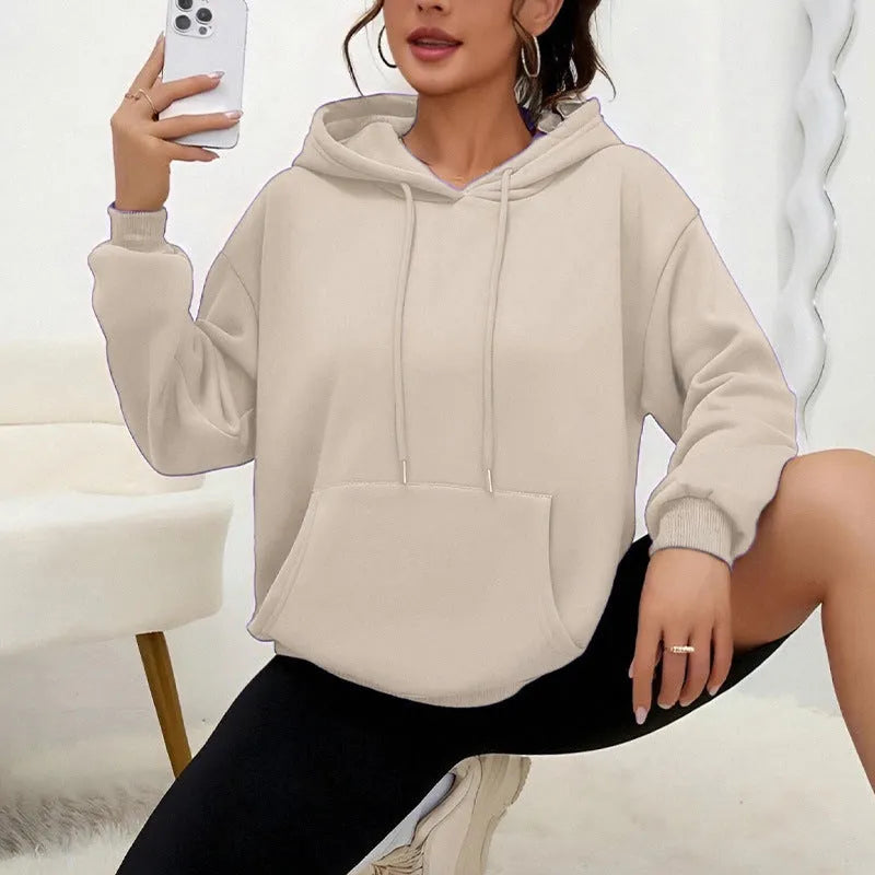 Woman wearing a loose grey drawstring waist sweatshirt with front pockets and long sleeves.