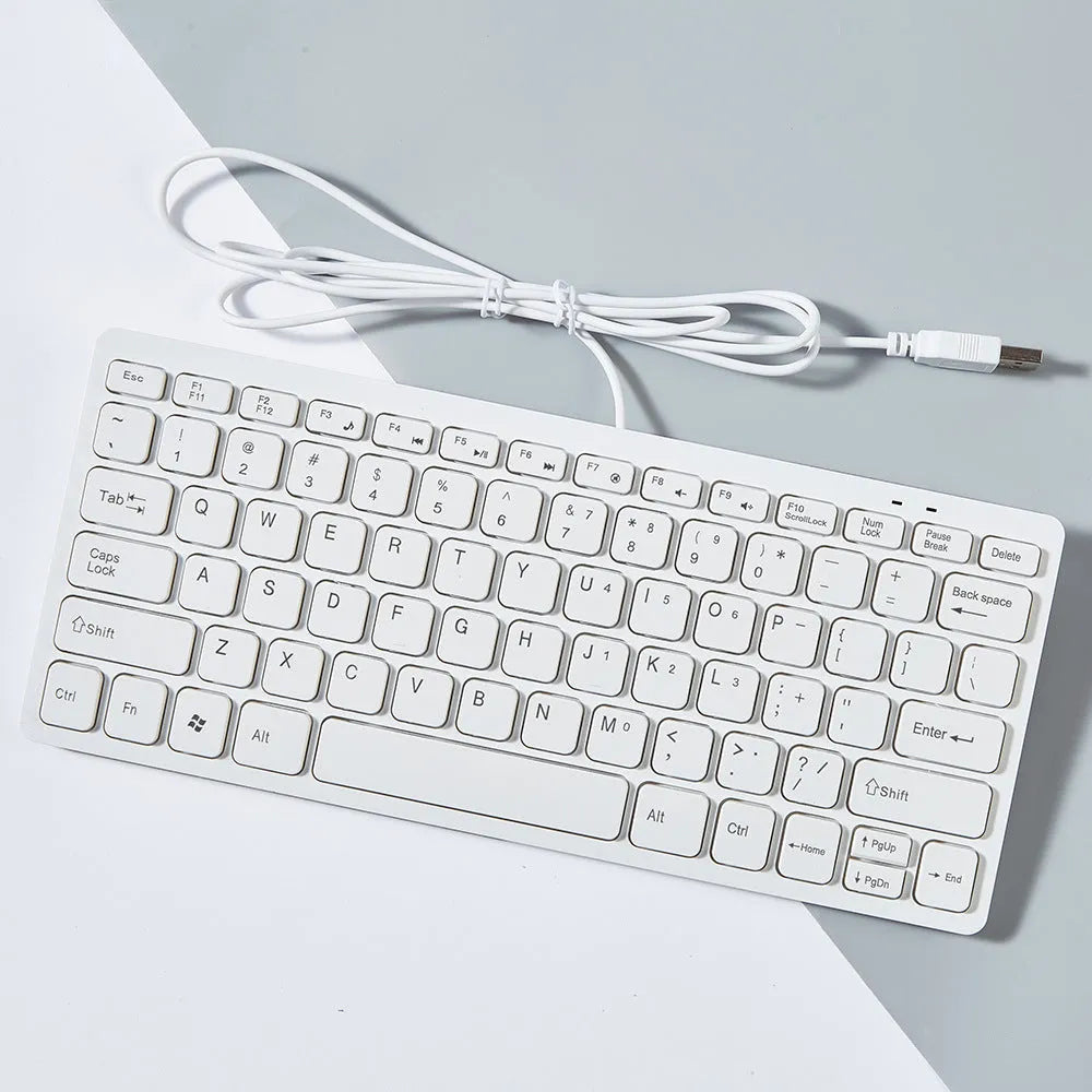 Compact USB wired keyboard in black, white, pink, or blue colour options on a desk.