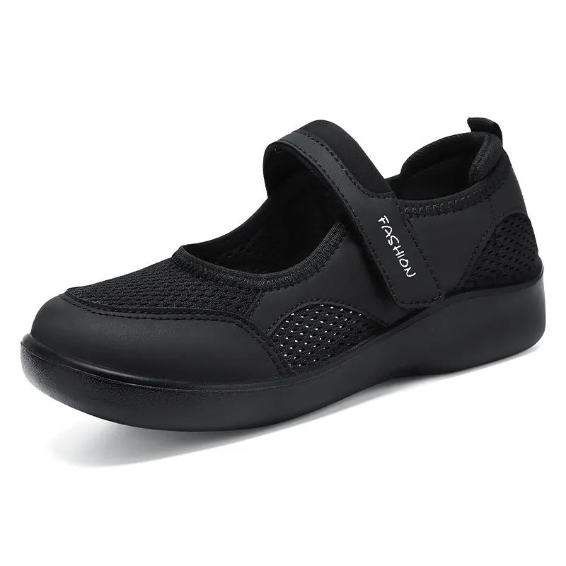 Women's grey casual slip-on shoe with mesh upper and Velcro strap on a flat sole.