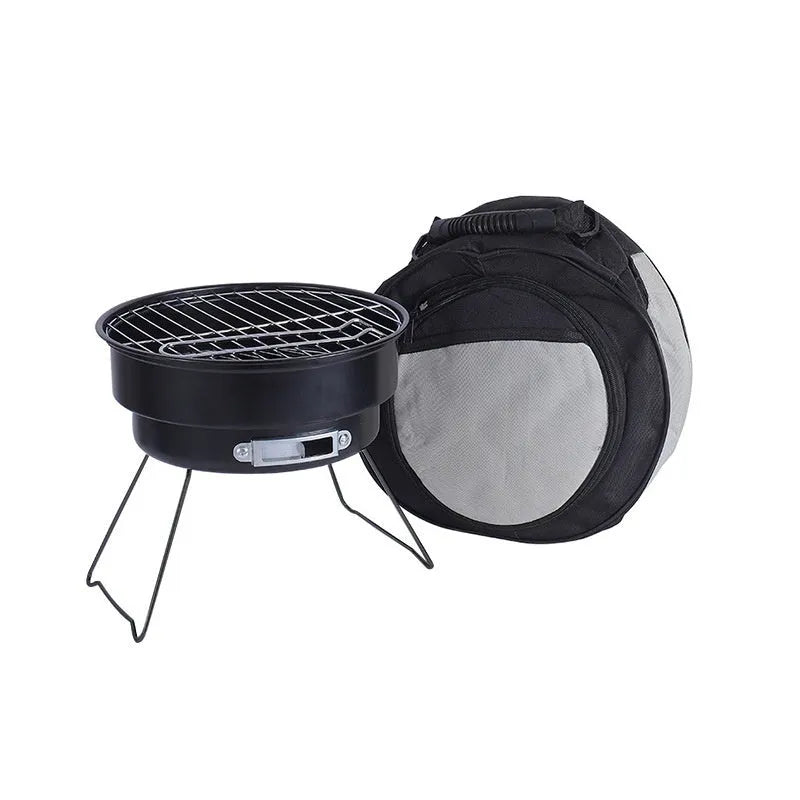 Small metal folding outdoor charcoal stove with mesh grill and tripod legs set up on grass.