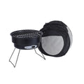 Small metal folding outdoor charcoal stove with mesh grill and tripod legs set up on grass.