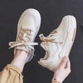Pink and beige low-top sneakers with a rubber sole and imitation leather upper.