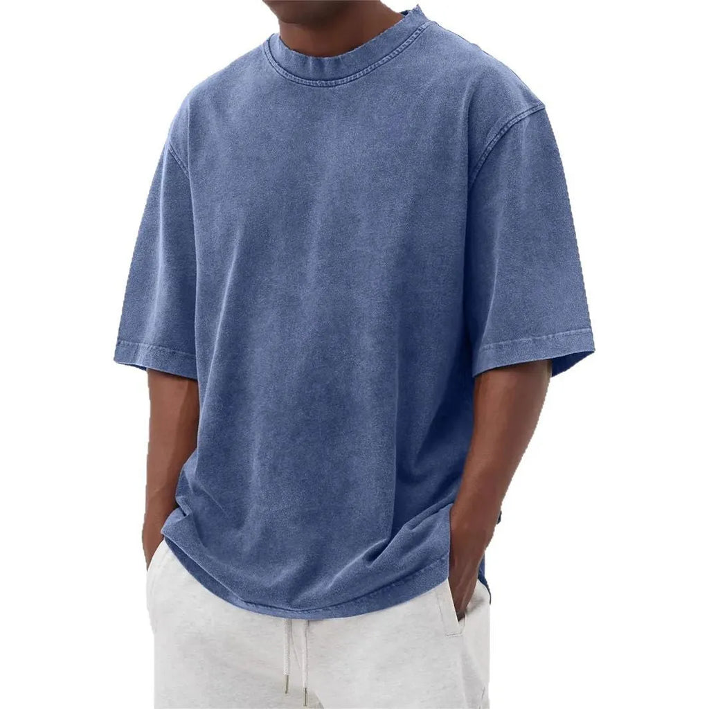 Man wearing a loose-fit, stone-washed distressed pullover T-shirt in a solid colour.