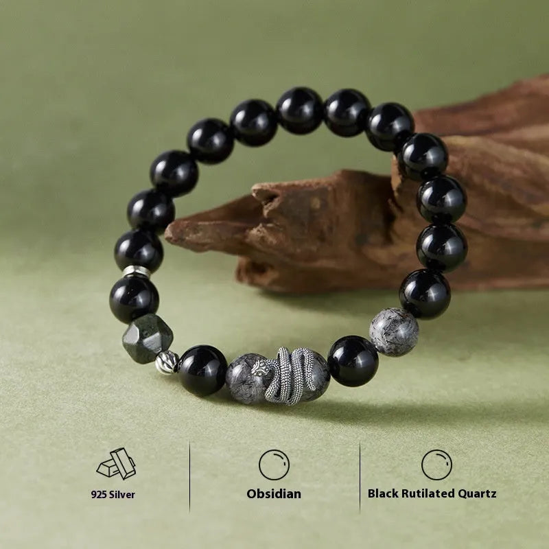Men's obsidian black snake bracelet made of sterling silver with retro zodiac styling on a wrist.