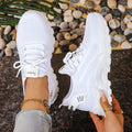 Women's low-top white mesh sports shoes with platform sole and front laces on a grey background.