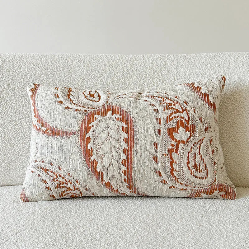 American-style jacquard cushion cover with paisley and flower pattern in amber colours on a sofa.