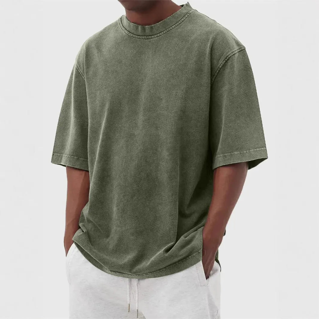 Man wearing a loose-fit, stone-washed distressed pullover T-shirt in a solid colour.