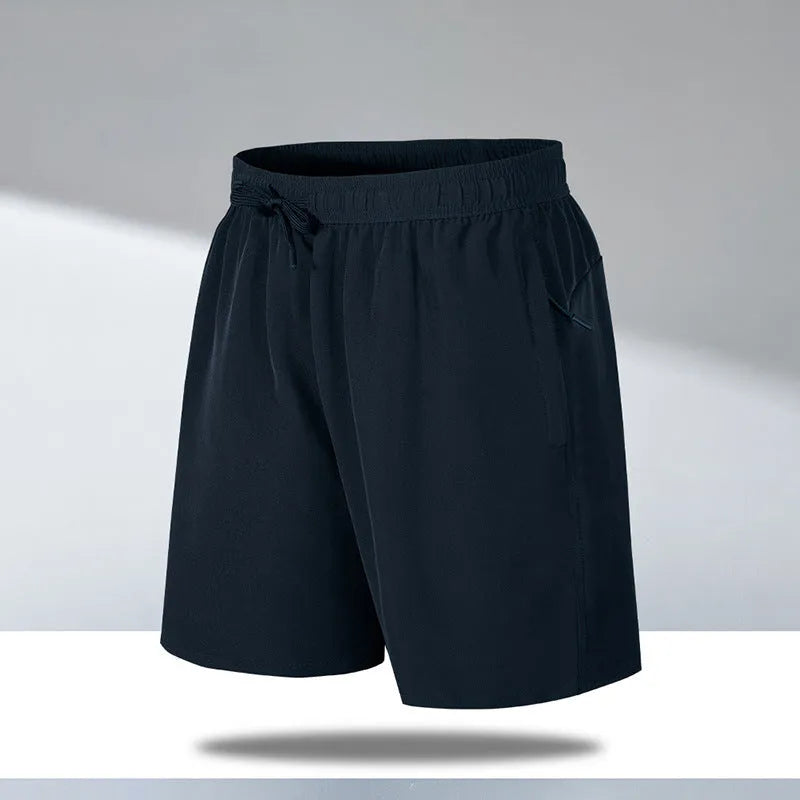 Man wearing loose fit black quick-dry sports shorts on a beach.