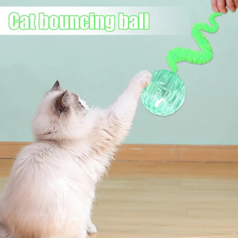 Interactive cat toy with purple bouncy ball and plush tail on wooden floor