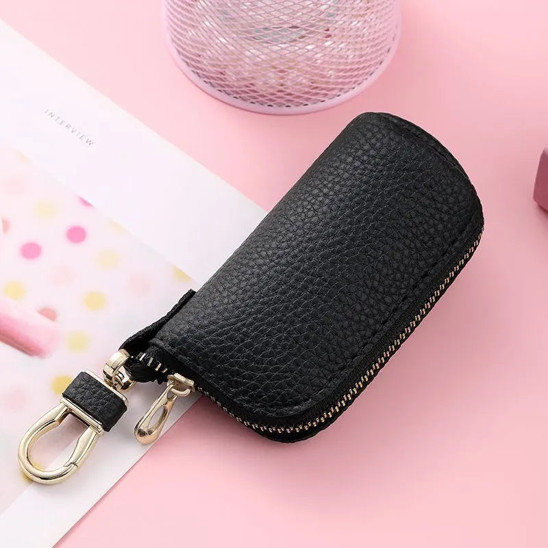 Simple black PU leather zipper key ring case on a grey background.