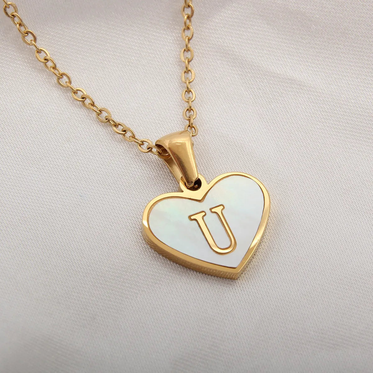 Gold heart necklace with white shell detail and personalised initial letter on adjustable chain