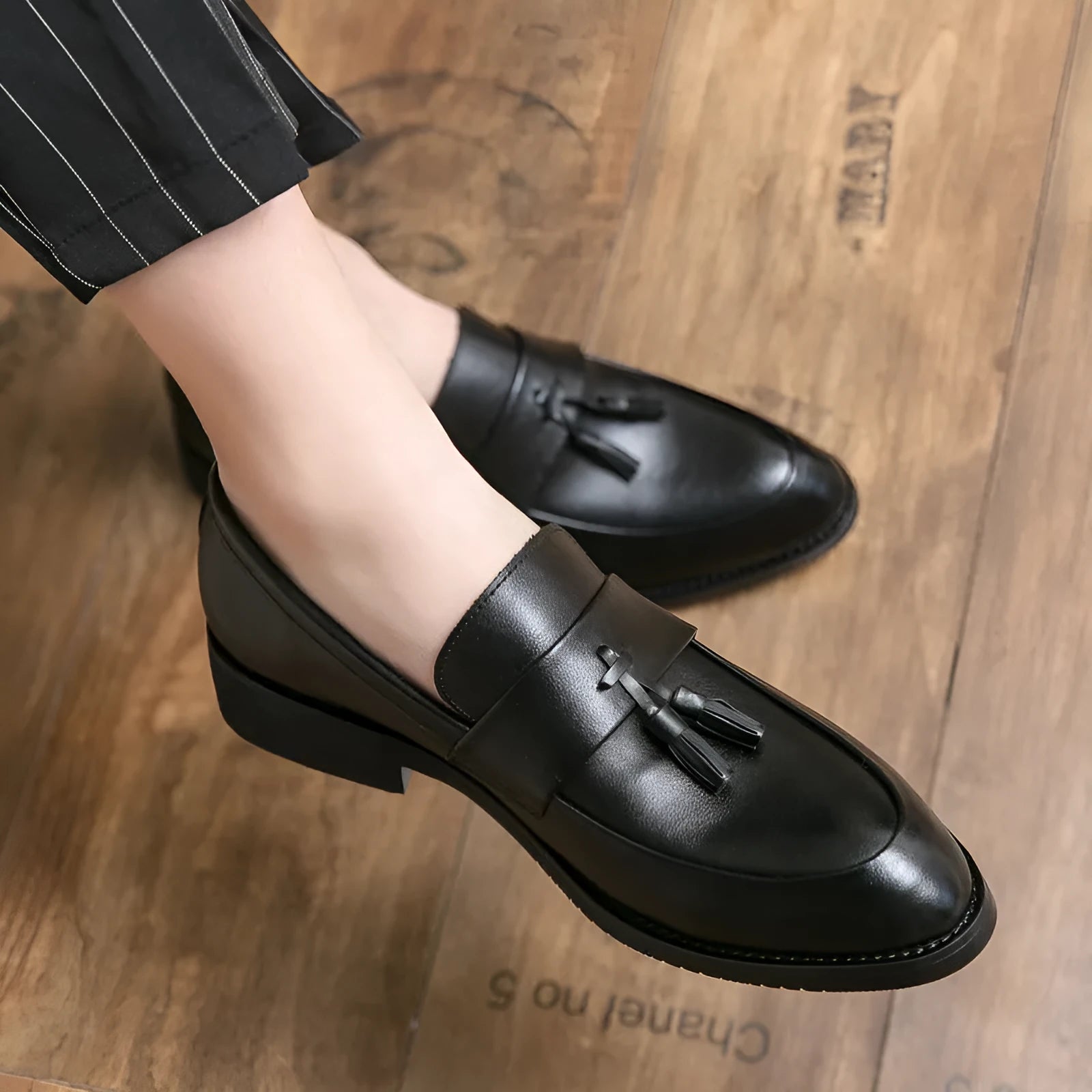 Men's black slip-on business casual shoe with a tassel detail on a low-top artificial PU upper.