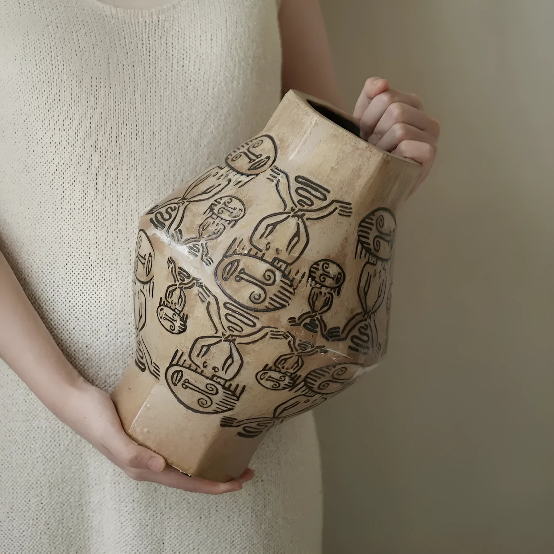 Hand-painted ceramic vase with carved tribal totem art in cylindrical shape.