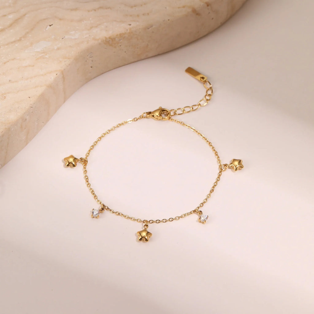 Women's stainless steel bracelet with 18K gold plating and a geometric zircon star pendant on wrist.