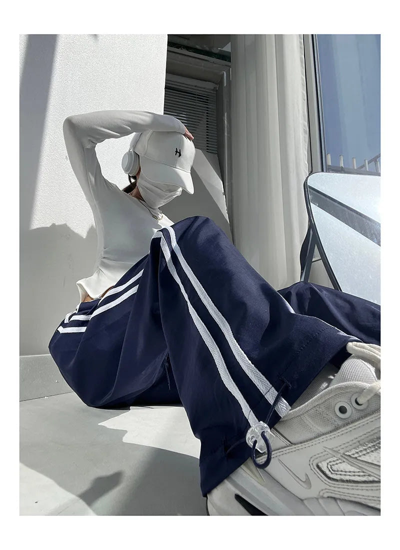 Women's navy blue loose straight-leg trousers with thin fabric and ribbon parallel bars contrast detail.
