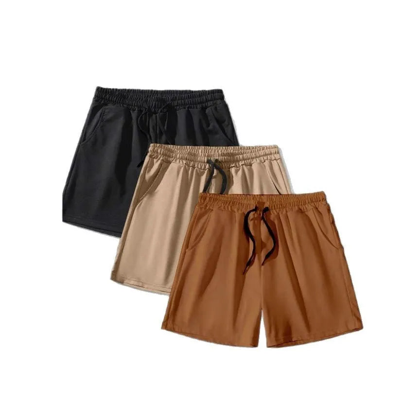 Three men's solid colour drawstring shorts laid flat showing loose fit and adjustable waistband.