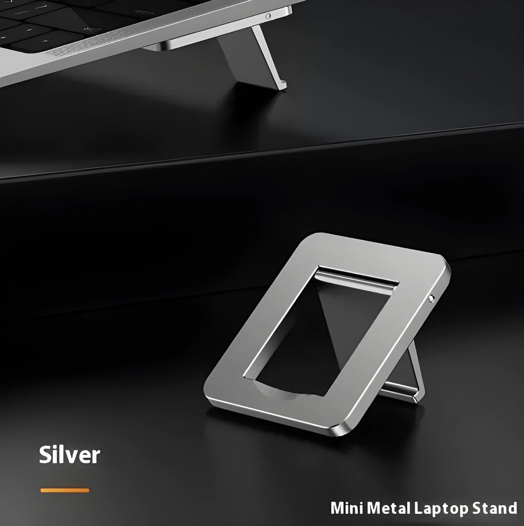 Compact silver aluminium folding laptop stand on a desk next to a wireless keyboard.