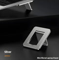 Compact silver aluminium folding laptop stand on a desk next to a wireless keyboard.