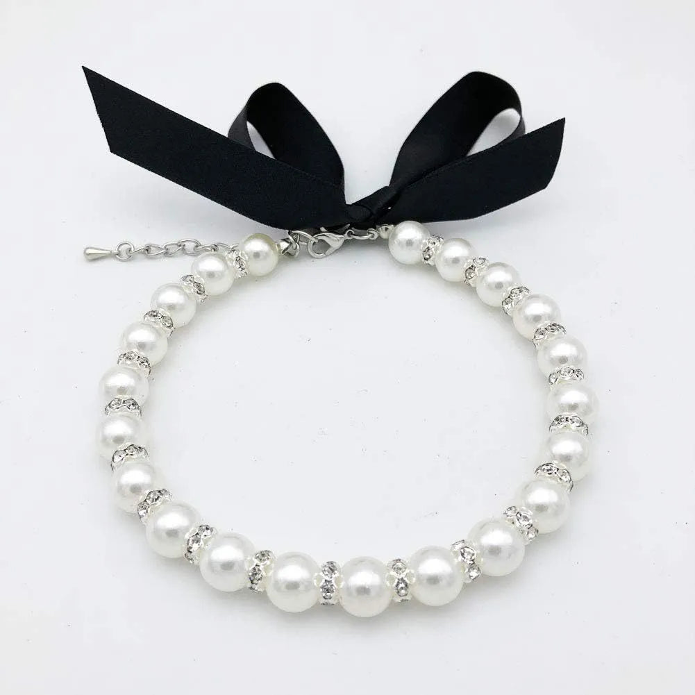 Small dog wearing adjustable pearl and rhinestone necklace with soft ribbon bow in blue colour