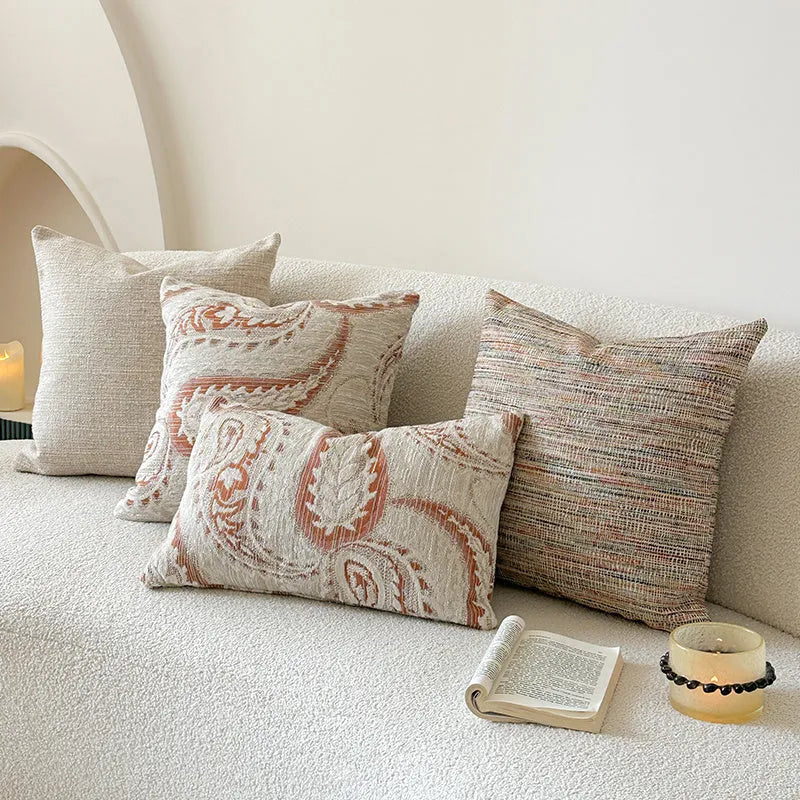 American-style jacquard cushion cover with paisley and flower pattern in amber colours on a sofa.