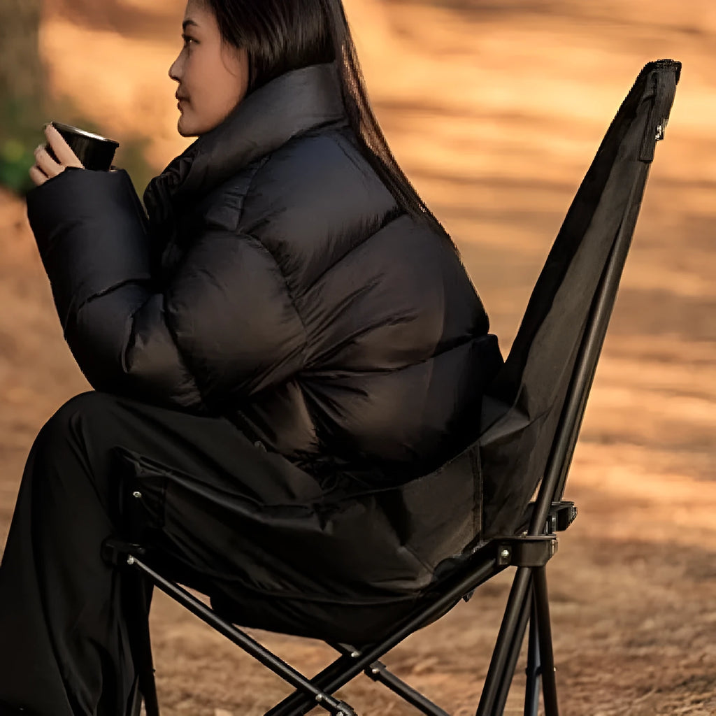 Night Black portable folding moon chair in use outdoors, showing its reclined design and carry handle.